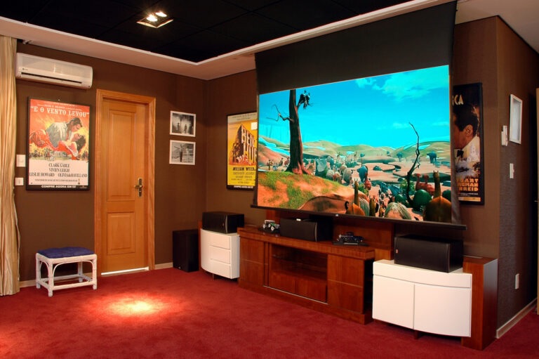Sala de home theater com tela de projeção, caixas de som e receiver